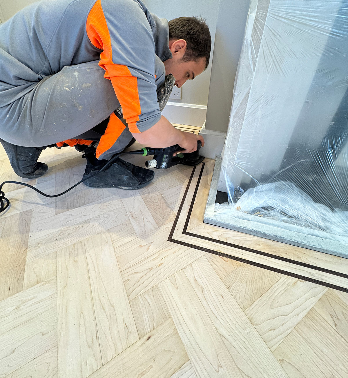 fitting-flooring-in-process image of flooring professionals fitting flooring underlay alongside grey boards